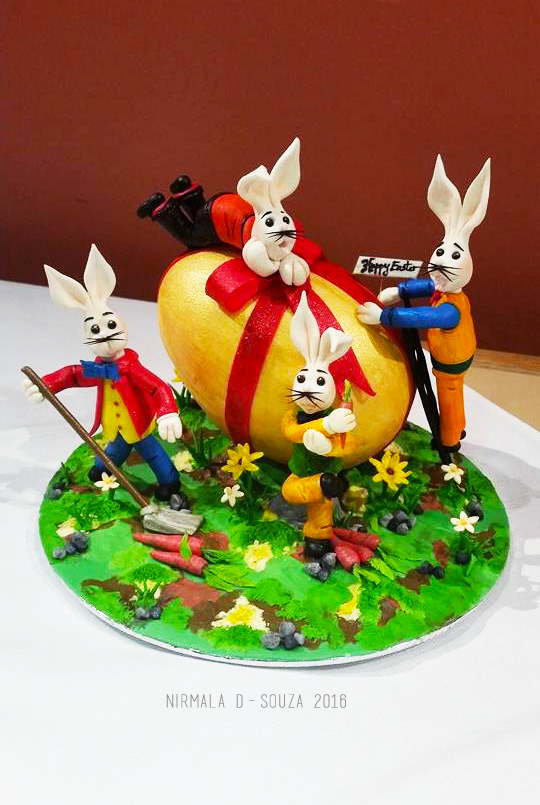 Easter Bunnies decorating large gold egg cake by Nirmala D Souzav
