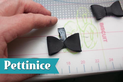 Cut strips of black fondant about 3cm long by about 3/4cm wide. Brush glue along strip and place the folded ovals opposite each other as shown.  Fold the strip over and secure it, hiding seams at the back.