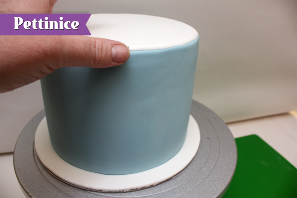 Attach the circle of white fondant using water on top of the cake covered with the blue fondant.