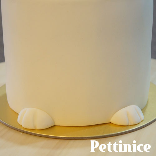 Using a little bit of water, stick the paws to the front of the cake.