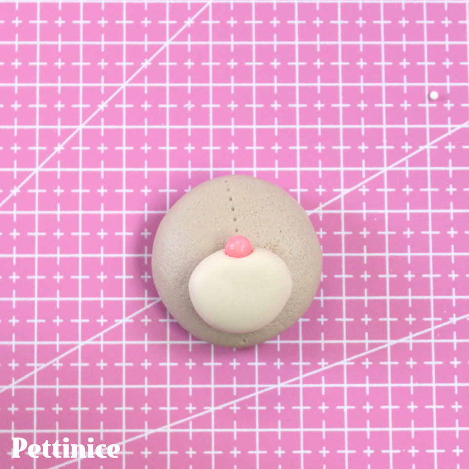 Add some White Pettinice to create a lighter shade for the snout and stick a smaller flattened ball on the bottom half of the head.  I used a pink sprinkle for the nose.