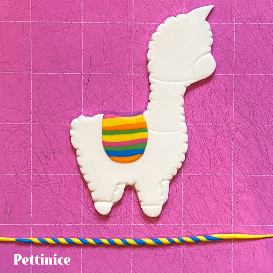 Moisten the llama where the saddle will go with a little water or edible glue and stick the it down.  Choose 2 colours and roll a long thin sausage out of each and twist them together.