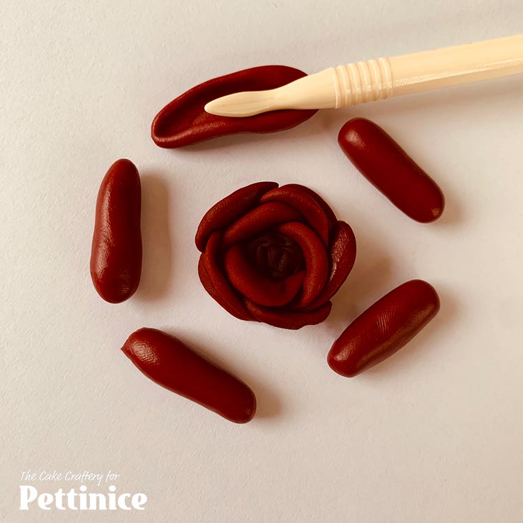 With same dark ruby red, repeat with 5 x 1cm (0.5g/pea-sized) sausage shapes. Wrap these around the 1st row of 3 petals, overlapping each other again.