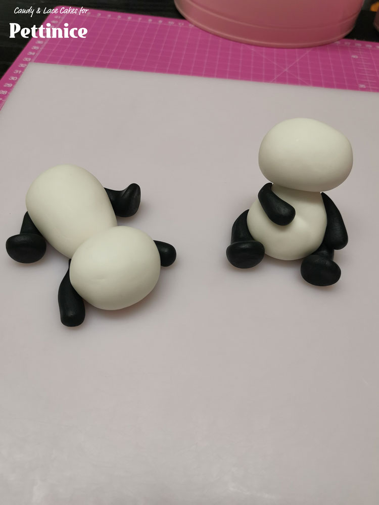 Attached the front and back legs onto each body with edible glue and a paintbrush, so that sitting panda has his arms resting on himself and lying panda has his arms and legs on either sides of his body.