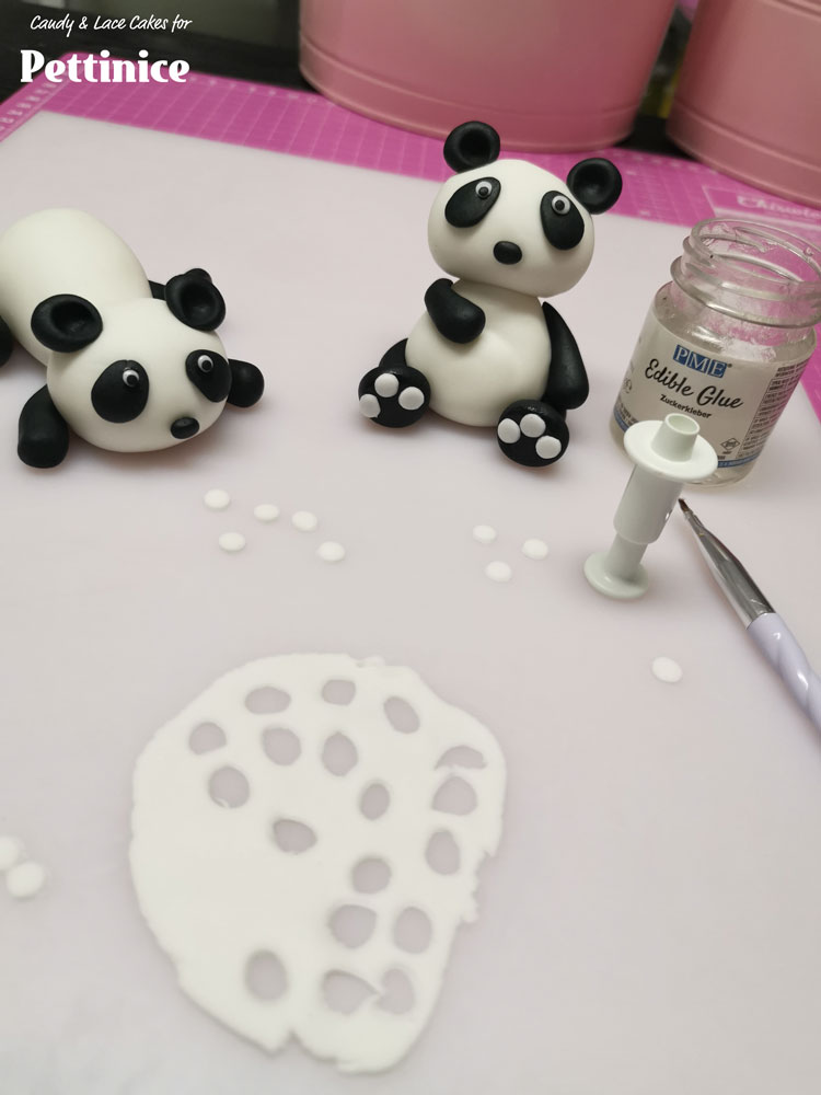 Lastly use your smallest round plunger cutter to cut little circles out of thinly rolled white Pettinice. Stick them onto the feet as well as onto the eye patches.   Add a tiny black speck in each eye and your panda's are done!