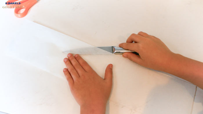 For the sides of the pan, fold your baking paper into thirds just like this.  Use a sharp knife to cut along the creases and separate the paper.