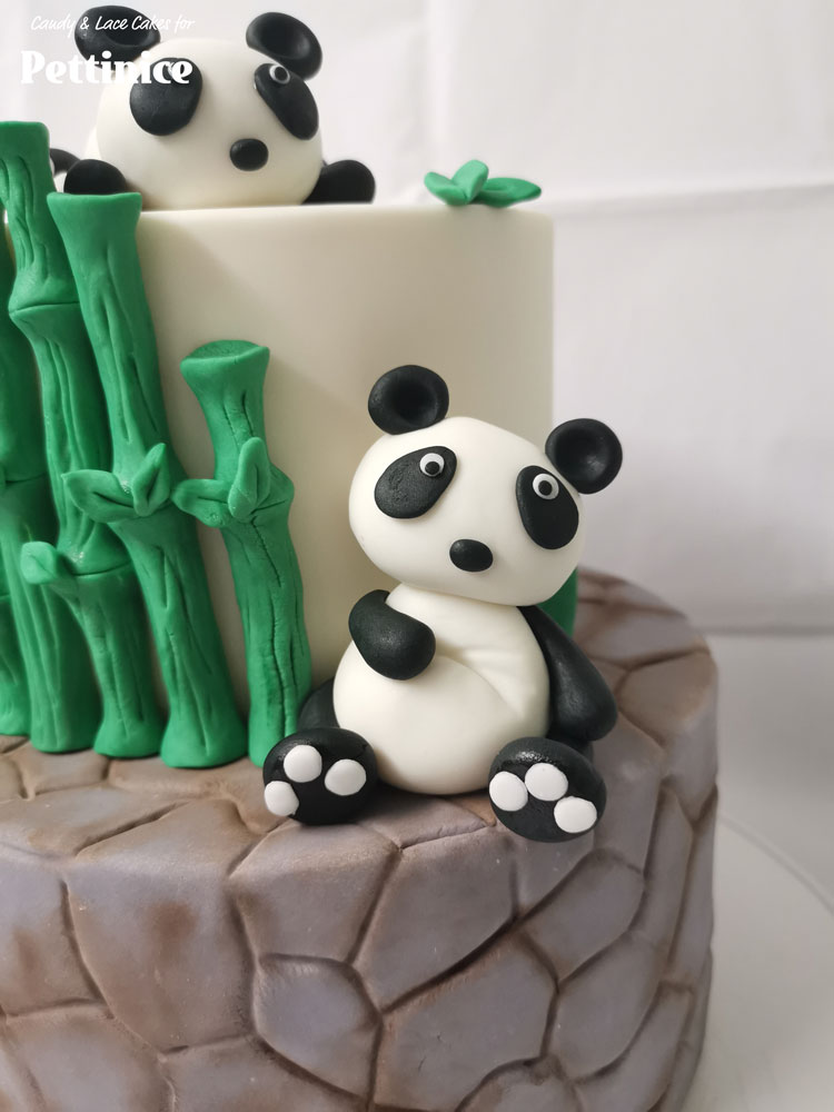 Lastly, place your 2 Pandas onto the cake. The lying panda on top of the top tier and the sitting panda next to the top tier, resting on the bottom tier.