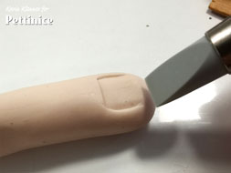 Using your flat tipped tool make indents for the nail and wrinkles and creases for the finger